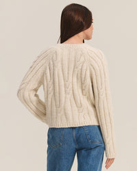 A person with long brown hair is shown from the back against a plain light background, wearing the Allison Long Sleeve Crew Cardi in Ivory by Velvet by Graham & Spencer and blue jeans.