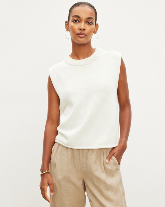 Woman in a Velvet by Graham & Spencer Aster Cap Sleeve Crew Top in Milk and beige trousers posing against a plain background.