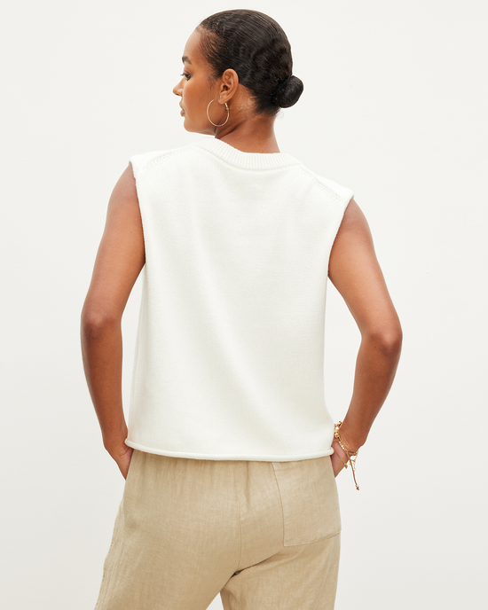 Woman wearing a sleeveless white Velvet by Graham & Spencer Aster Cap Sleeve Crew Top in Milk and beige trousers facing away from the camera.