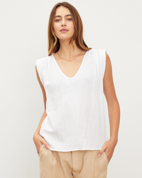 Woman wearing a Jayla Scoop Neck Top in White by Velvet by Graham & Spencer and beige trousers standing against a plain background.