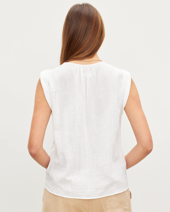 Woman standing with her back to the camera, wearing a Jayla Scoop Neck Top in White and beige pants from Velvet by Graham & Spencer.