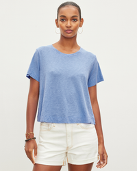 A woman in a Velvet by Graham & Spencer Lula Swing Tee in Wave and white shorts standing against a plain background.