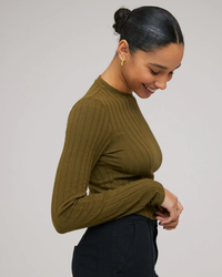 A person in a Bella Dahl Long Sleeve Crop Crew Neck in Deep Rosemary smiling and looking downwards.