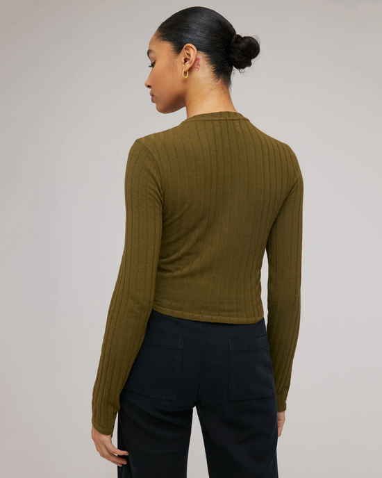 A woman seen from behind wearing a Bella Dahl Long Sleeve Crop Crew Neck in Deep Rosemary and black trousers.
