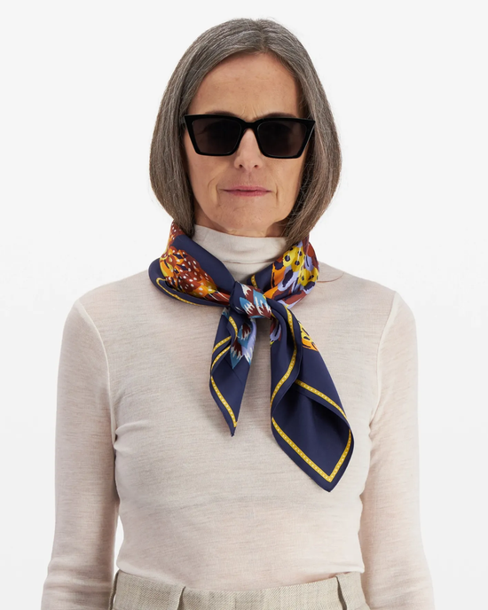 Woman wearing sunglasses and an Inoui Editions Carre 65 Hulule in Navy scarf, a luxury accessory, tied around her neck.