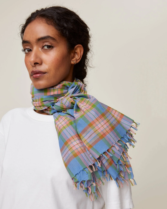 A woman wearing a white top and a Mois Mont Scarf No 722 in Nordic Blue with fringe detailing.