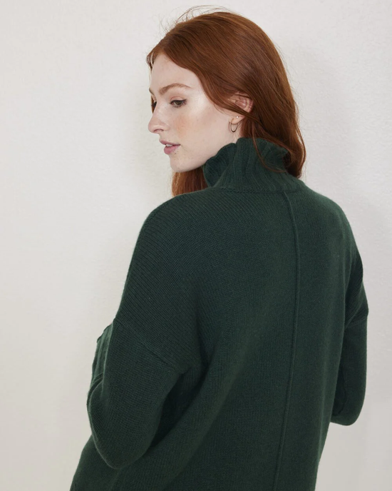 Woman in a green, oversized Elsie Oversize Turtleneck in Jade sweater from Not Monday looking away from the camera.