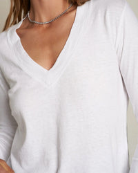 A person wearing the Fiona Long Sleeve Recycled V Neck in White by perfectwhitetee and a delicate chain necklace, photographed from shoulders to waist with partially visible hair.