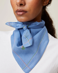 A woman wearing a blue Bandana No 656 in Nordic Blue tied neatly around her neck from Mois Mont.