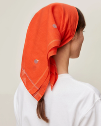 Woman wearing a Mois Mont Bandana No 656 in Poppy Red and white shirt, viewed from behind.