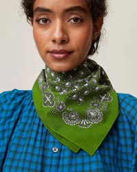 A woman wearing a Bandana No 675 in Green Tea from Mois Mont and a blue plaid shirt.
