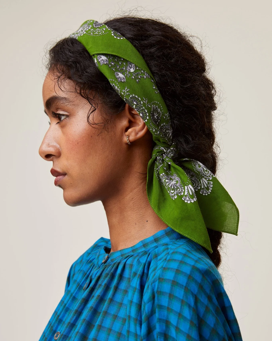 Side profile of a woman wearing a Bandana No 675 in Green Tea by Mois Mont with a floral pattern and blue plaid garment.