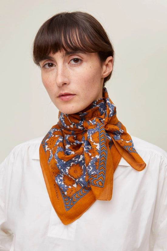 Woman with a Mois Mont Bandana No 680 in Terracotta and white blouse.