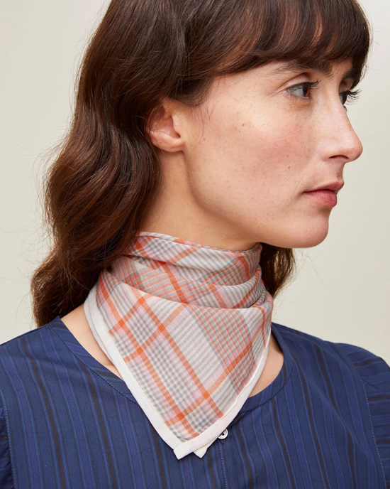 A woman with a side profile view wearing a Mois Mont Bandana No 712 in Poppy Red and a dark blouse.