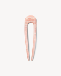 A pink Machete French Hair Pin in Apricot Shell Checker with a marble pattern on a white background.