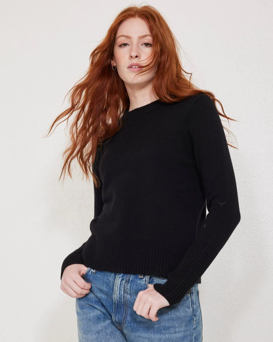 A woman with red hair wearing the Not Monday Jane Crewneck in Black and blue jeans.
