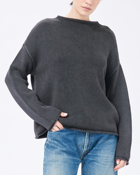 Woman wearing a Lamis Boatneck Sweater in Black by Demylee and blue jeans.
