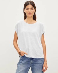 A woman in a Velvet by Graham & Spencer Hudson S/S Crew Neck Top in White and blue jeans standing against a plain background.