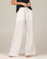 A person standing in Bella Dahl's Drawcord Wide Leg Pant in White and a black top with only the lower part of their torso and legs visible.