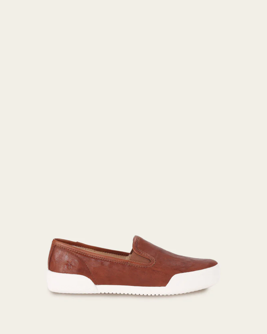 A single FRYE Mia Slip On in Cognac with a white sole displayed against a beige background.