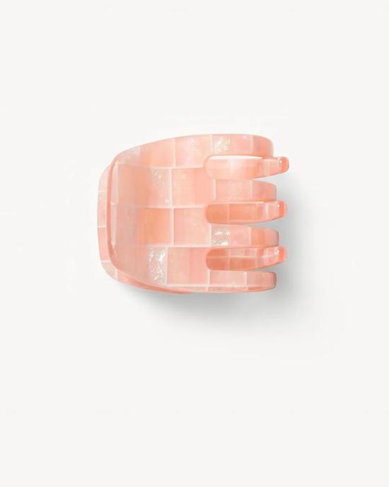 A translucent pink Italian acetate Machete Mini Claw in Apricot Shell Checker positioned against a white background.