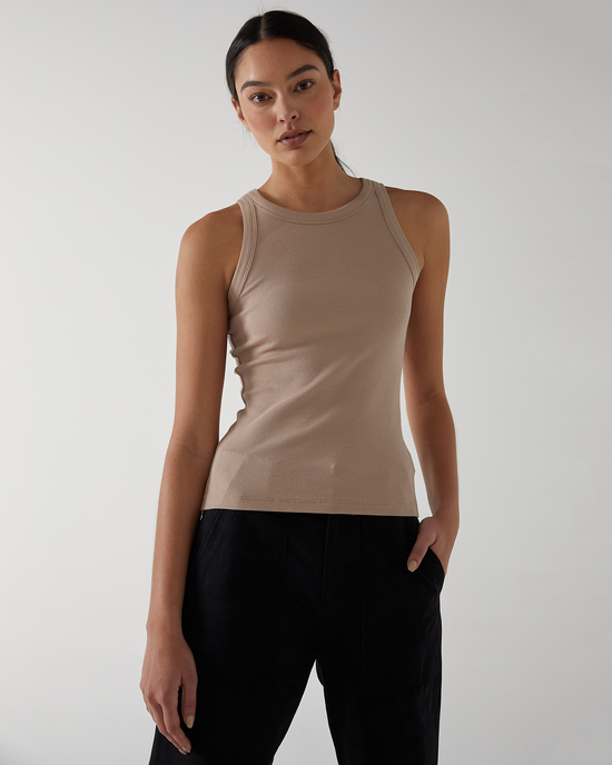 A woman in a Velvet by Graham & Spencer Cruz Tank in Nude and black pants standing against a light background, looking directly at the camera.