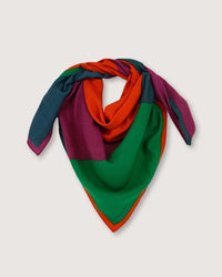 Presented against a plain backdrop, the Bandana No 751 in Poppy Red by Moismont is an oversized triangular scarf crafted from a luxurious blend of wool, silk, and cashmere, showcasing vibrant sections of green, orange, teal, and magenta.