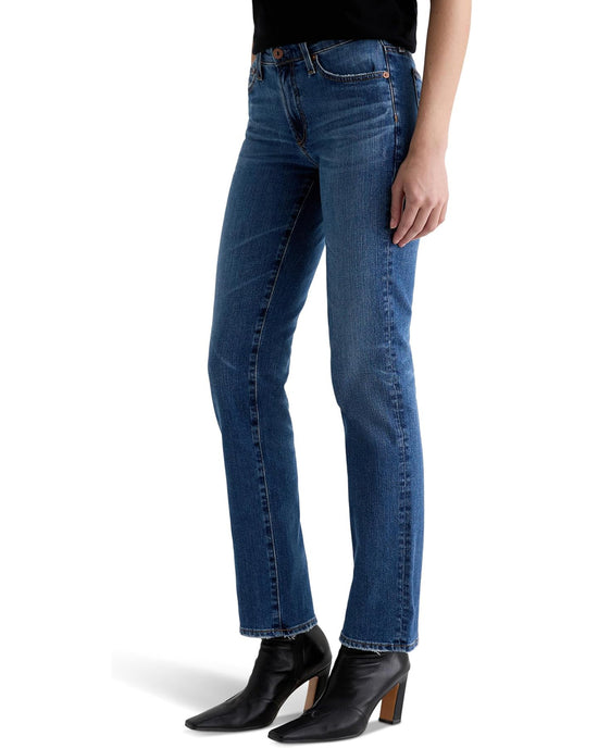 A person wears AG Jeans' Sandra Low Rise Straight in 15Ys Prague, paired with a black top and black heeled ankle boots, standing against a white background.