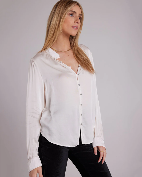 Woman posing in a Bella Dahl Shirred Button Up Blouse in Soft Alabaster from the holiday capsule collection and black pants.