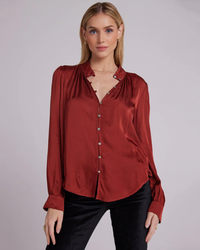 Woman posing in a Bella Dahl Shirred Button Up Blouse in Warm Brandy and black pants from their holiday capsule collection.