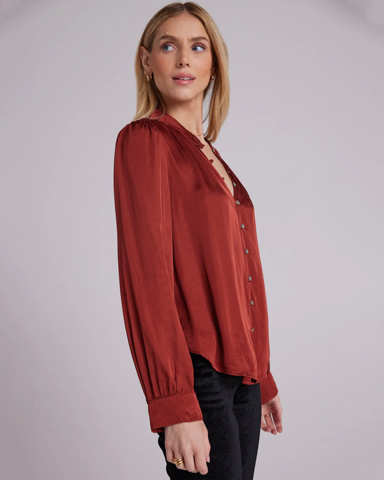 Woman wearing a rust-colored Bella Dahl Shirred Button Up blouse and black trousers against a neutral background.

Woman wearing a Warm Brandy Bella Dahl Shirred Button Up blouse and black trousers against a neutral background.
