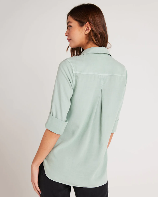 Woman wearing a light green, TENCEL™ Lyocell Bella Dahl Shirt Tail Button Down in Oasis Green with rolled-up sleeves viewed from the back.