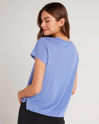 Woman wearing a Bella Dahl Side Slit V Neck Tee in Peri Blue and black pants viewed from the side.