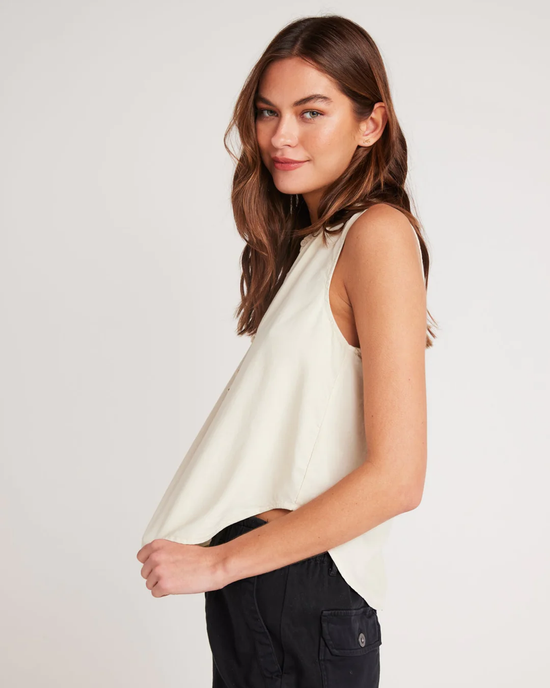 Woman in a Bella Dahl Sleeveless Pullover in Cliffside Tencel Lyocell top and black pants turning to look at the camera.