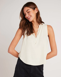 Woman smiling and looking down, wearing a sleeveless Bella Dahl Sleeveless Pullover in Cliffside made of Tencel Lyocell with a zipper neckline.