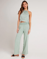 A woman modeling a light green Bella Dahl Smocked Waist Wide Leg Pant in Oasis Green and matching high-waisted trousers made of TENCEL™ Lyocell.