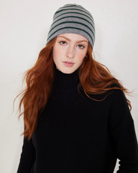 Woman with red hair wearing a Not Monday Tate Cashmere Beanie in Storm Grey & Jade Stripe and black turtleneck.