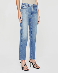 Product showcase of a pair of AG Jeans Saige High Rise Straight in 16Ys Cupola with a high waisted straight leg design, accompanied by black strappy high heels, without the upper body of the model visible.