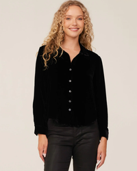 A woman with curly hair wearing a Bella Dahl Long Sleeve Clean Shirt in Black and black pants.