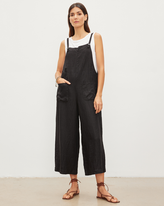 Woman standing in an Isabel Jumpsuit in Black by Velvet by Graham & Spencer and a white tank top with brown strappy sandals.