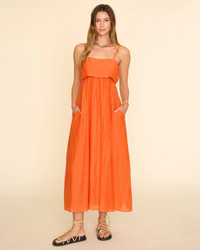 Woman in orange XiRENA Skyla Dress in Papaya cotton silk voile midi dress posing for the camera.