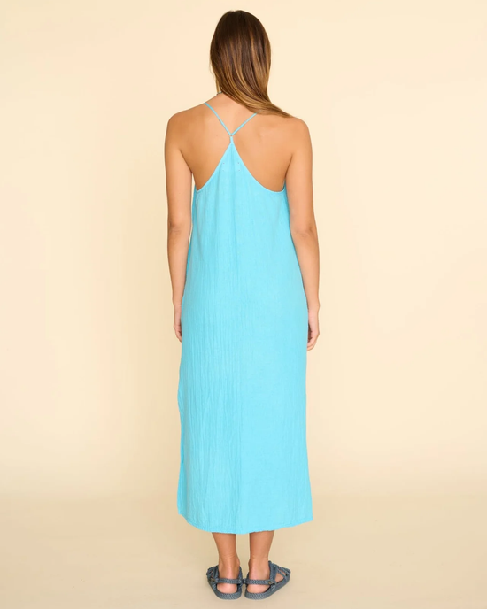 A woman wearing a Talia Dress in Sea Star, a double cotton gauze, blue sleeveless XiRENA dress with a crisscross strap design at the back.