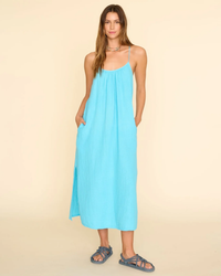 Woman wearing a double cotton gauze XiRENA Talia Dress in Sea Star with sandals standing against a neutral background.