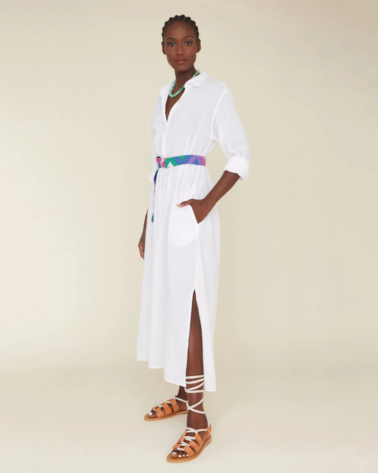 A woman posing in a white Cotton Poplin XiRENA Boden Dress with a colorful belt and strappy sandals.