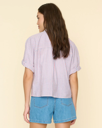 Woman wearing a button-down XiRENA Teddy Shirt in Firework Stripe and denim shorts viewed from behind.