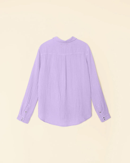A light purple XiRENA Scout Shirt in Viola, long-sleeve and made from 100% Cotton Gauze, displayed against a pale yellow background.