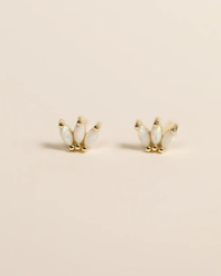 A pair of JaxKelly Opal Crown Stud - White earrings on a beige background.