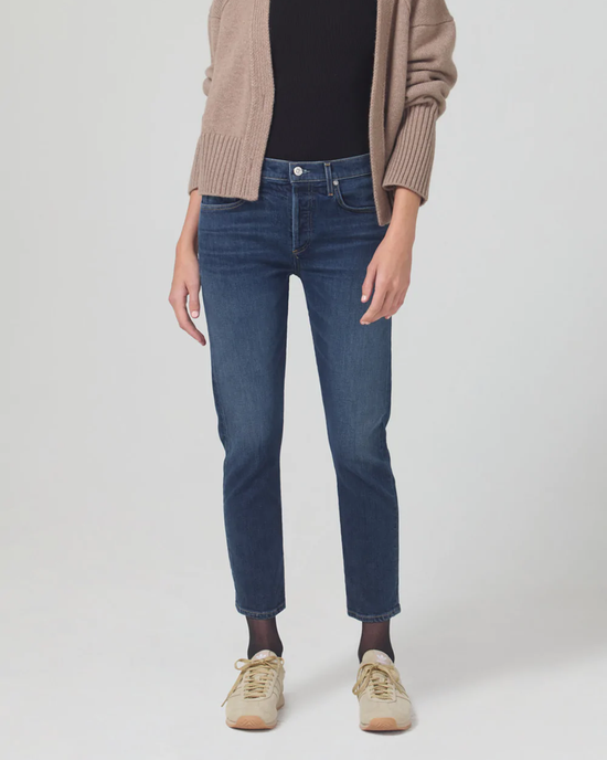 Woman wearing blue Citizens of Humanity Emerson Slim Boyfriend 27" in Trinket jeans, a black top, beige cardigan, and light brown sneakers.