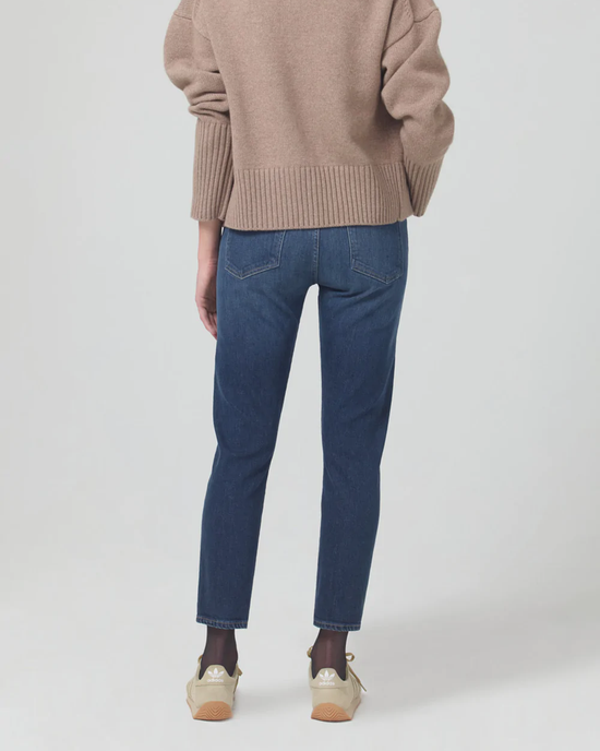 Person standing with back toward the camera wearing Citizens of Humanity Emerson Slim Boyfriend 27" in Trinket, a beige sweater, and cream-colored sneakers.