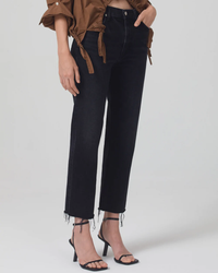 A person wearing black Citizens of Humanity Daphne Crop 26.5" Inseam in Peppercorn Jeans and high-heeled sandals with a brown jacket tied around the waist.